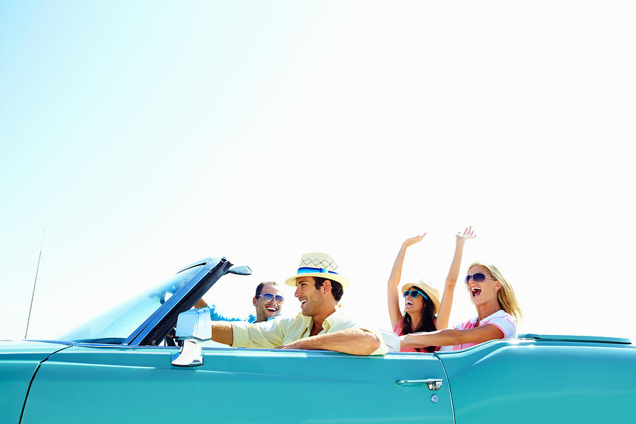 Cheerful young friends in a car on vacation trip Photograph by GlobalStock