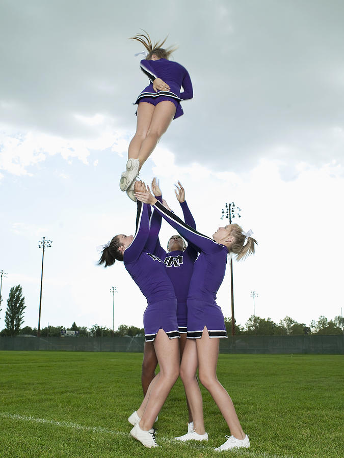 Cheerleaders Throwing Girl into the Air Photograph by Tony Anderson