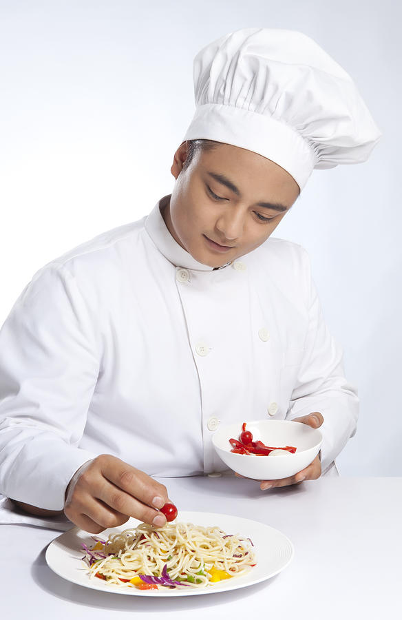 Chef placing cherry tomato on plate of noodles Photograph by Ravi Ranjan