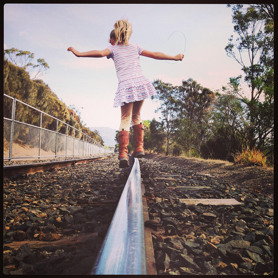 Child balancing & walking along railway line alone Photograph by Jodie Griggs