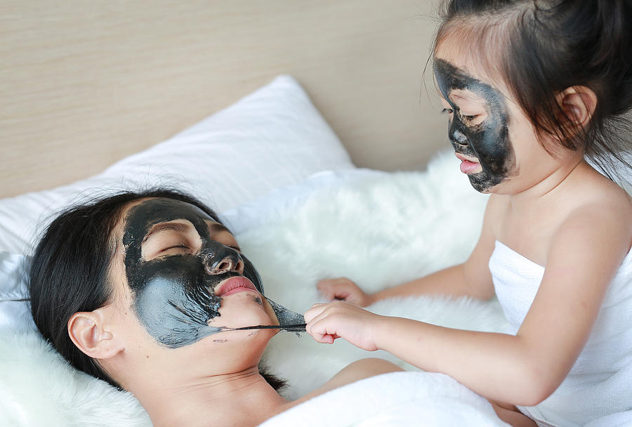 Child girl removed black mask from her mother, clean face. Photograph by Golfx