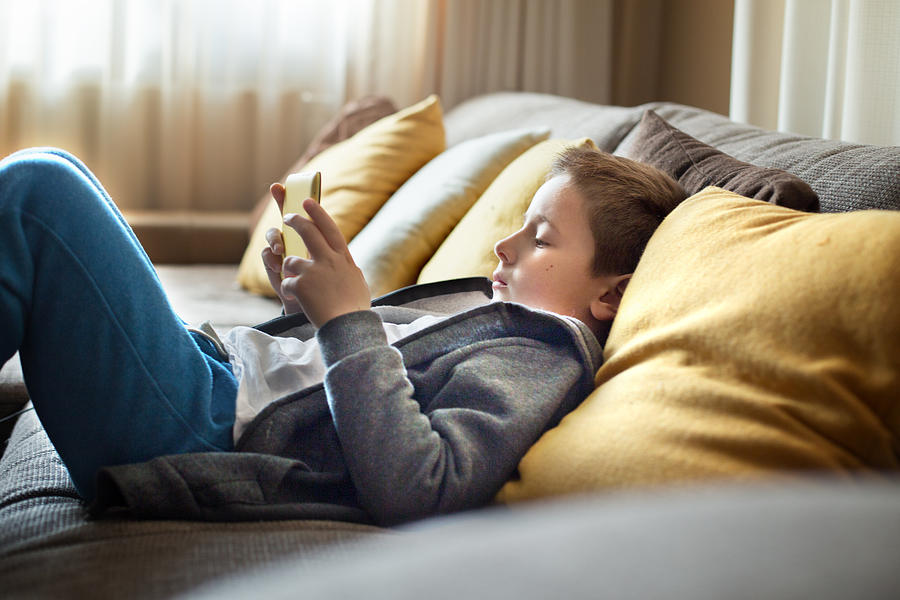 Child laying on couch with tablet Photograph by Stefka Pavlova