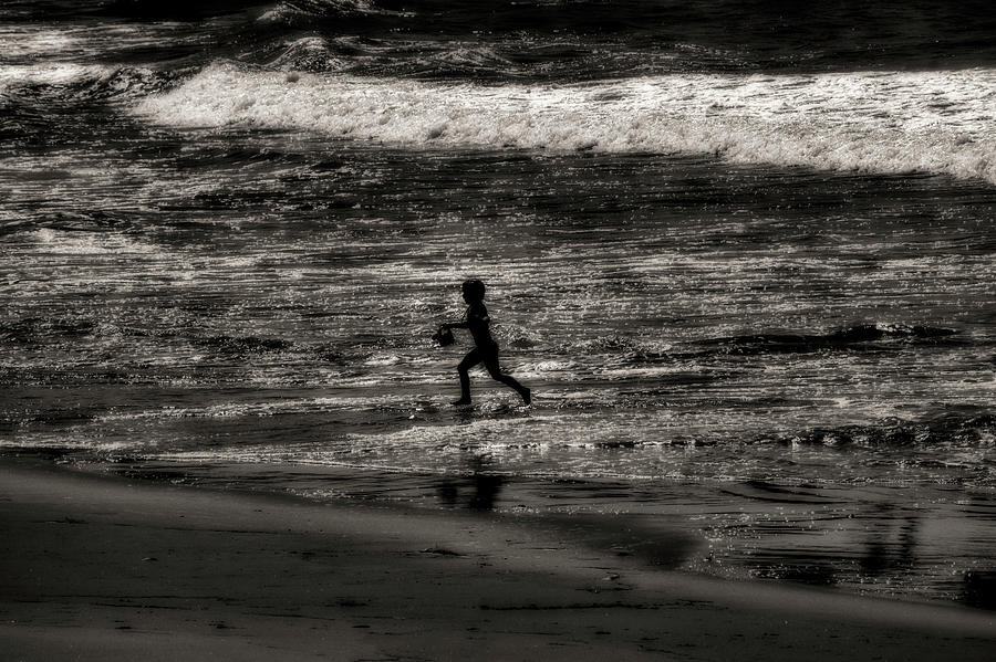 Child running in the ocean with sand bucket Photograph by Dan Friend