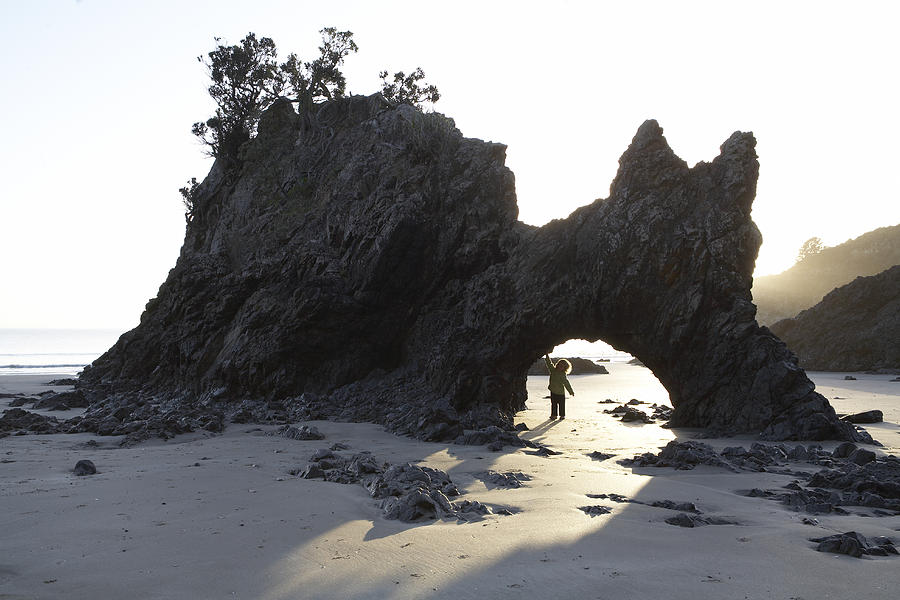 Child under rock formation by the sea Photograph by Heidi Coppock-Beard