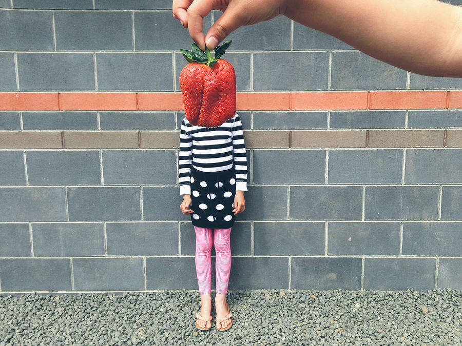 Child with large strawberry in front of face Photograph by Jodie Griggs