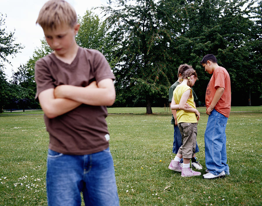 Children (9-12) standing in park, boy with arms crossed in foreground Photograph by Digital Vision