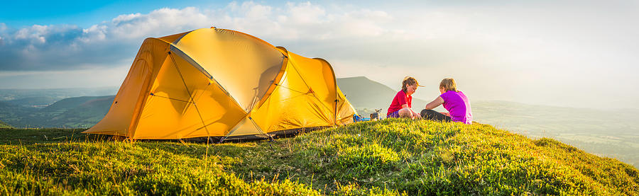 Children camping on idyllic summer mountain top beside tent panorama Photograph by fotoVoyager