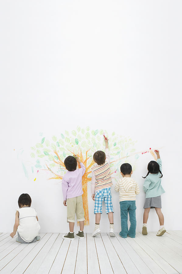 Children drawing a tree with markers Photograph by BLOOMimage