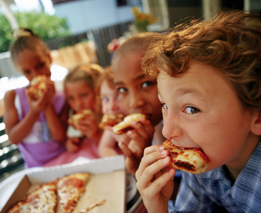 Children eating pizza outdoors Photograph by Burke/Triolo Productions