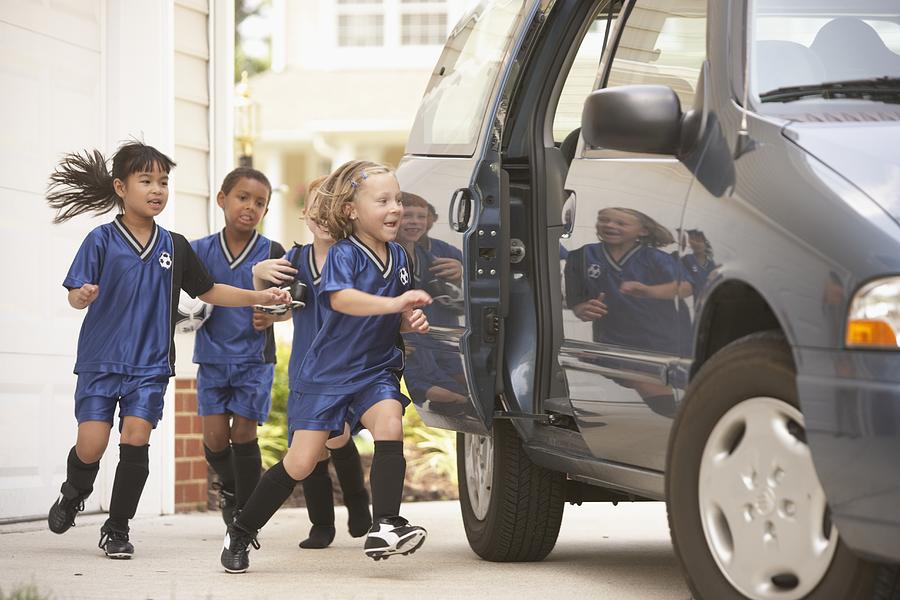 Children in soccer outfits getting into car Photograph by Ariel Skelley