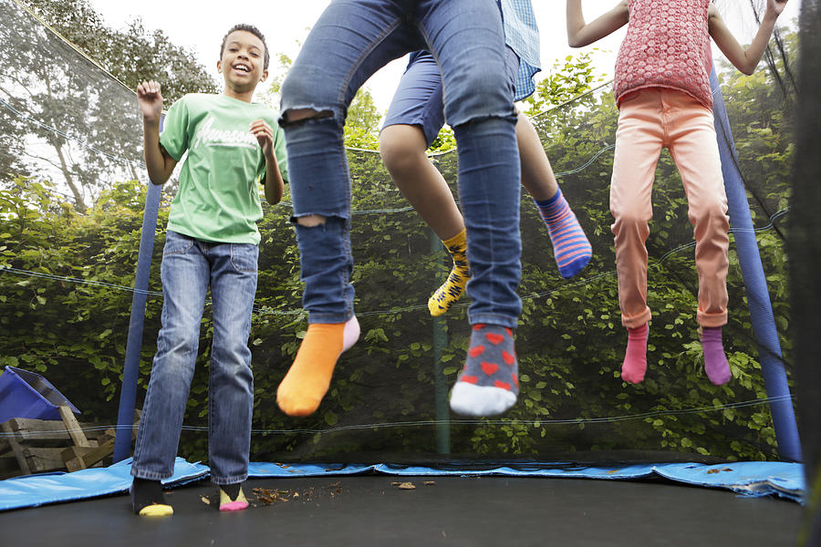 Children jumping on trampoline Photograph by Peter Cade