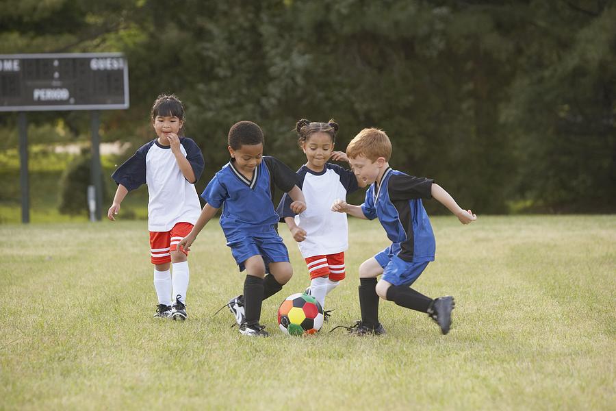 Children playing soccer outdoors Photograph by Ariel Skelley