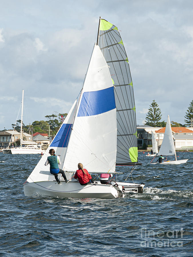 Children racing two sailboats close, side by side almost touchin Photograph by Geoff Childs