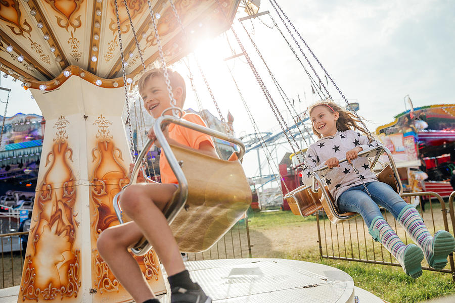 Children Riding on the Swings at the Fairground Photograph by SolStock