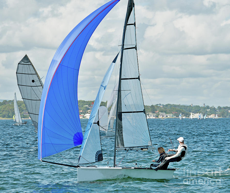 Children Sailing Racing Small Sailboat With A Blue Spinaker On A Coastal Lake. Commercial Use Photo. Photograph