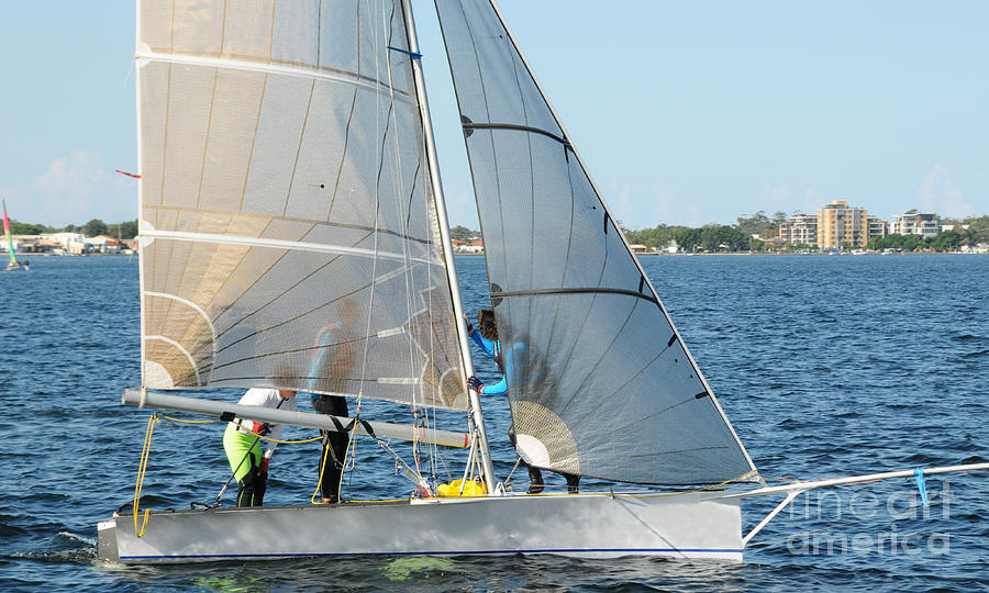 Children Sailing small dinghy with white sails up-close on an in Photograph by Geoff Childs