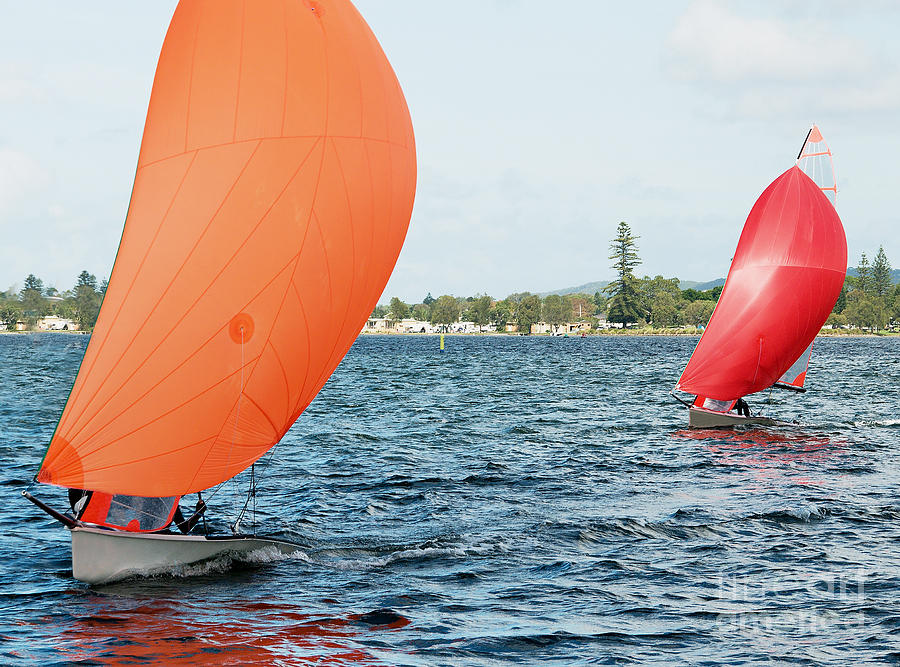 Children Sailing small sailboat with colourful orange and red sa Photograph by Geoff Childs
