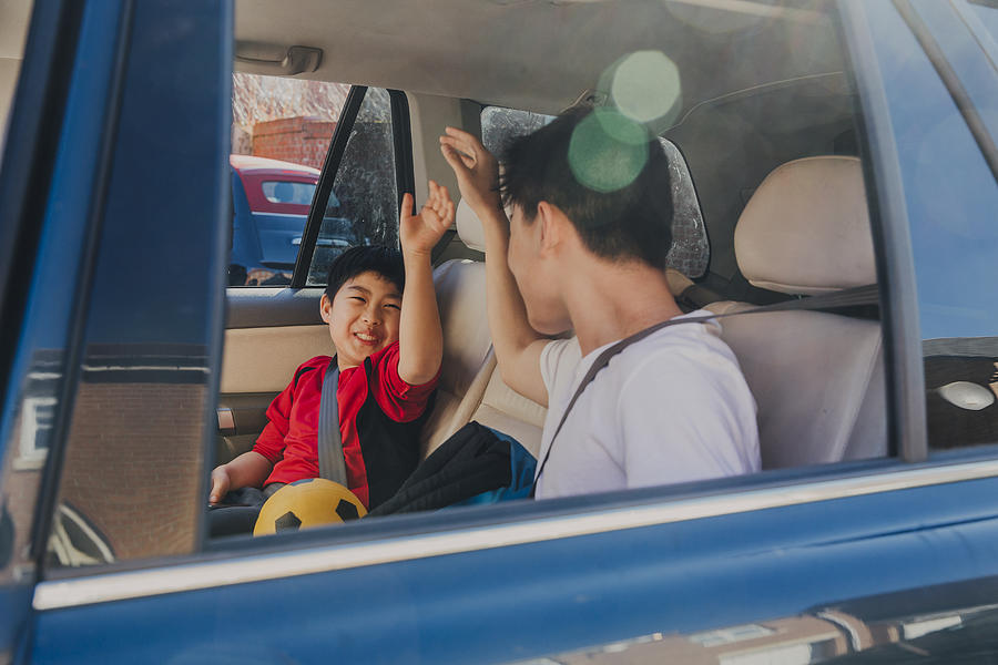 Chinese Kids Laughing in Backseat Photograph by SolStock
