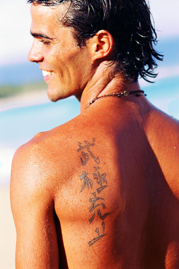 Chinese symbols tattooed on mans shoulder Photograph by Thinkstock