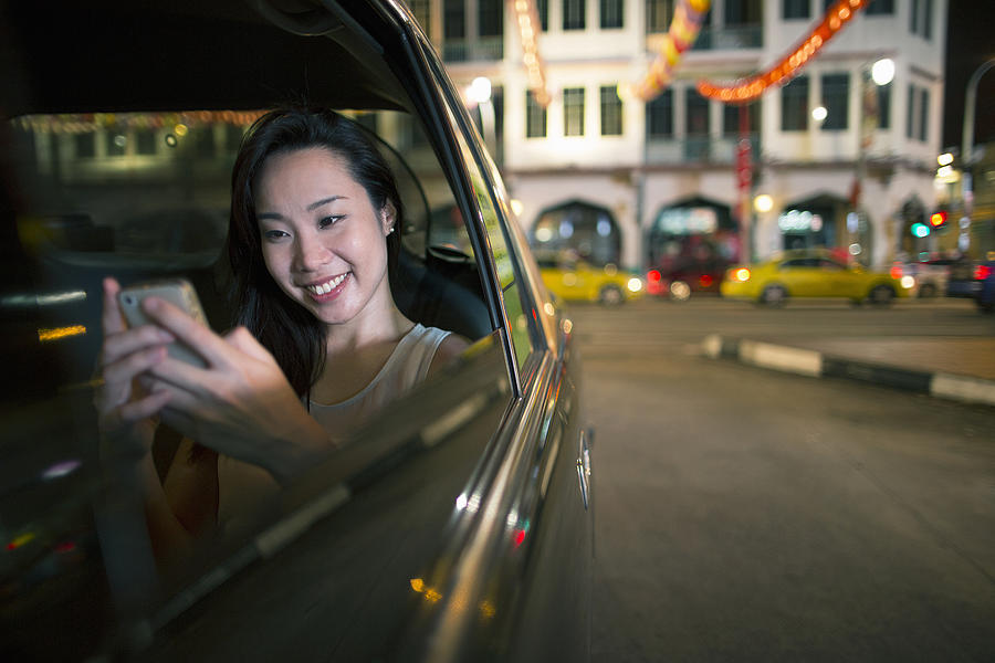 Chinese woman in car with smartphone Photograph by Eternity in an Instant