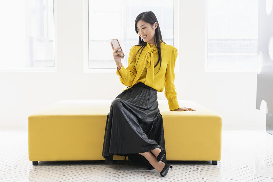 Chinese woman on yellow bench with phone Photograph by JohnnyGreig