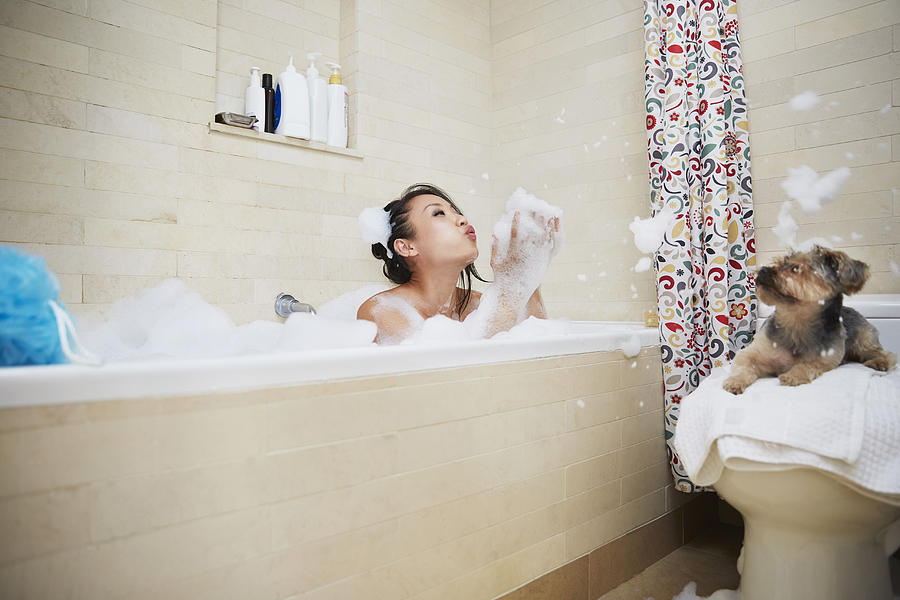 Chinese woman playing in bubble bath with dog Photograph by Jasper Cole