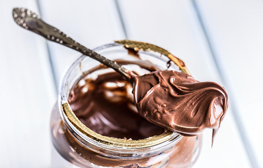 Chocolate spread in spoon. A jar of hazelnut chocolate spread Photograph by MarianVejcik