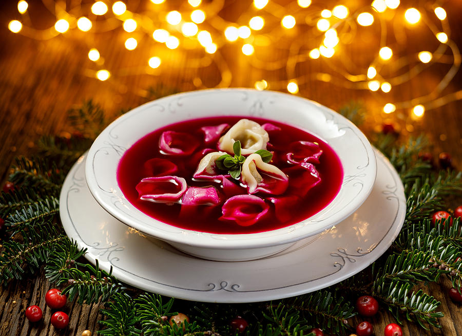 Christmas beetroot soup, red borscht with small dumplings with mushroom filling in a ceramic white plate on a wooden table Photograph by Zi3000