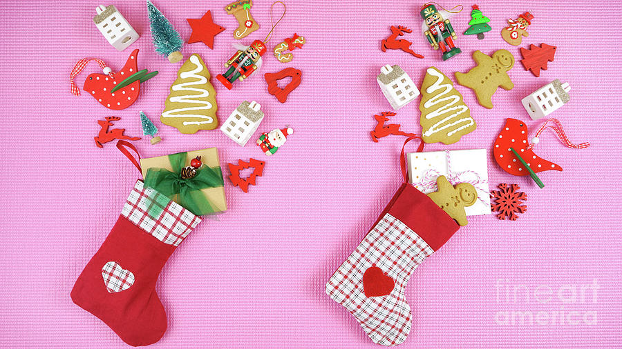 Christmas concept with stockings filled with gifts on a pink background. Photograph by Milleflore Images