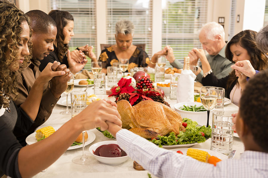 Christmas:  Family prays before eating holiday dinner. Photograph by Fstop123