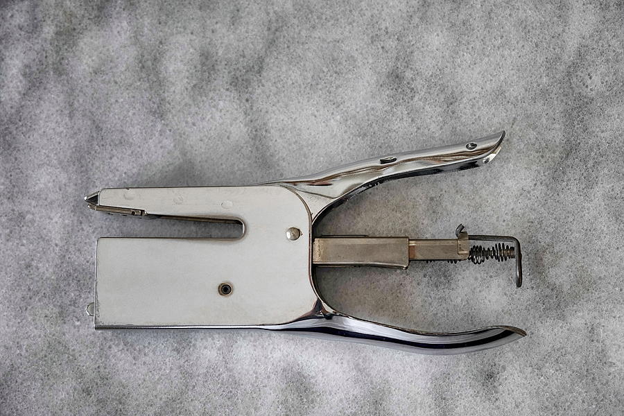 Chrome plated metal stapler on grey marble surface. Photograph by Emreturanphoto