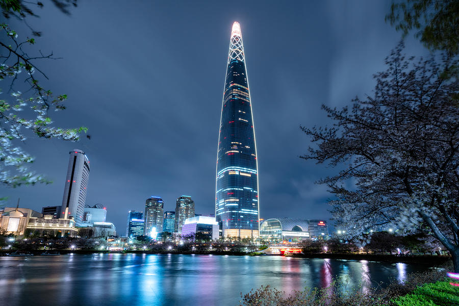 Cityscape of Seoul downtown city skyline with cherry blossom at night, Aerial view of skyscraper at Seokchon Lake at nightand sakura around lake. The amazing modern building at Seoul city, South Korea Photograph by Mongkol Chuewong