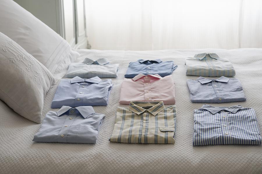Clean shirts ordered on a bed Photograph by Moodboard