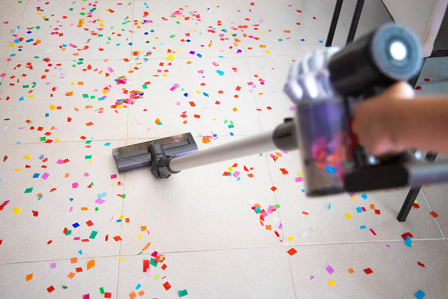 Cleaning home floor with vacuum after party with confetti. Photograph by Artur Debat