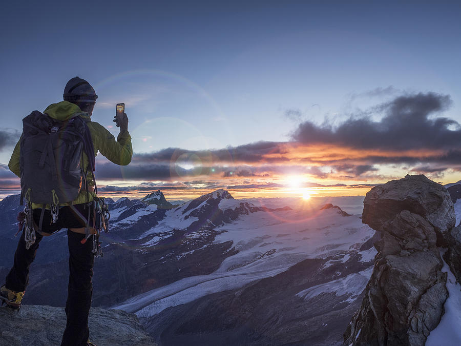 Climber on a peak photographing sunrise with smart Photograph by Buena Vista Images