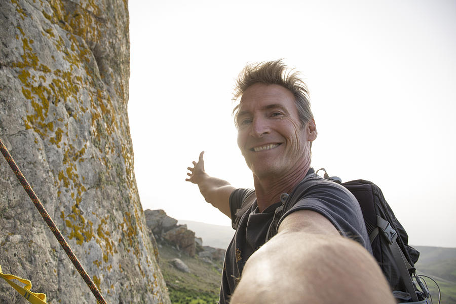 Climber takes selfie form mountain wall, above sea Photograph by Ascent/PKS Media Inc.