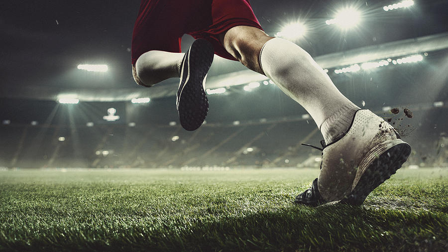 Close up football or soccer player at stadium in flashlights - motion, action, activity concept Photograph by Anton5146