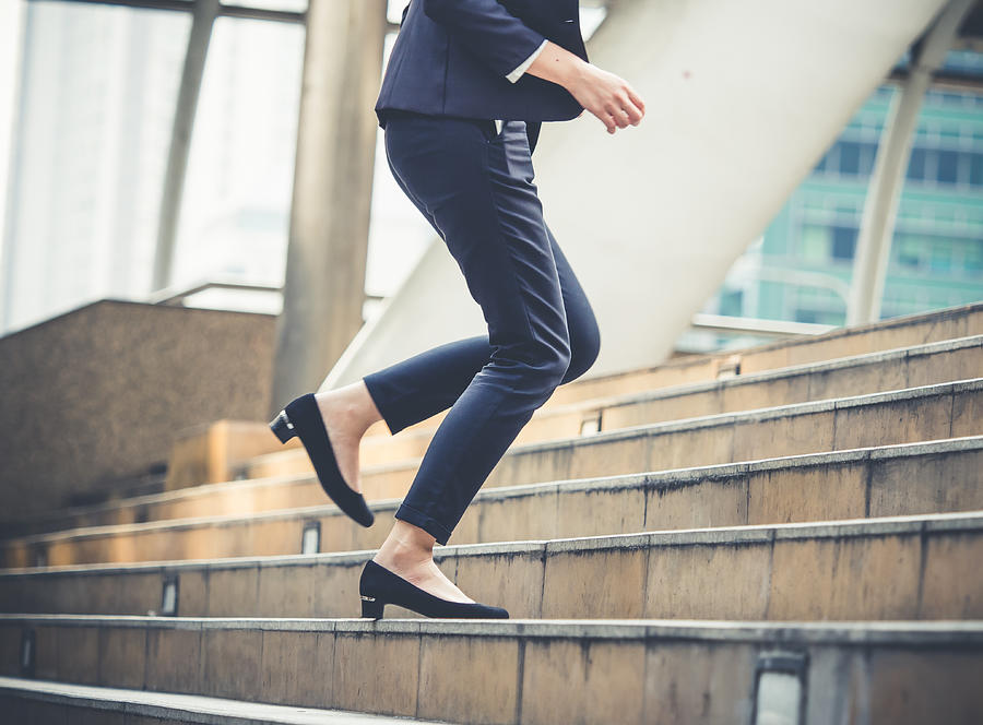 Close up legs of businesswoman walking stepping up stair in modern city, business growth, go up, success, grow up business concept Photograph by Nattakorn Maneerat