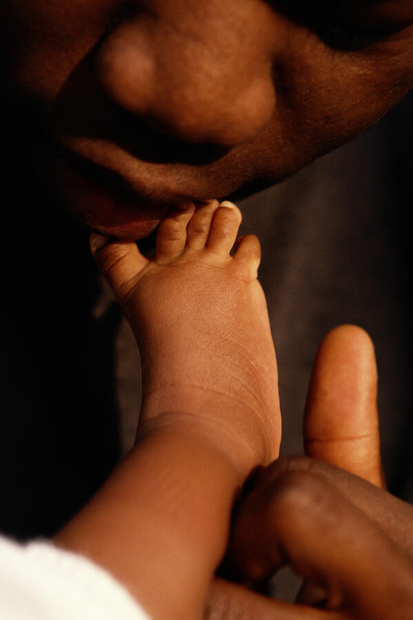Close-up Of A Black Father Kissing Babys Foot Photograph by Jean Mahaux