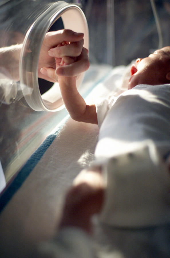 Close Up Of A Caucasain Newborn Baby Laying In An Incubator As A Nurse Takes The Baby By The Hand Photograph by Photodisc