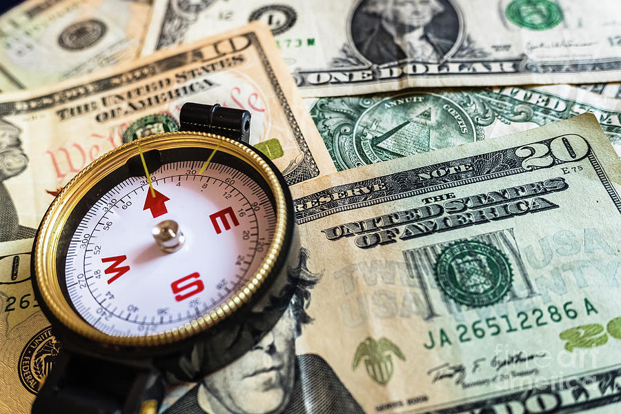 Close-up of a compass on dollar bills, guide for making smart investment decisions. Photograph by Joaquin Corbalan