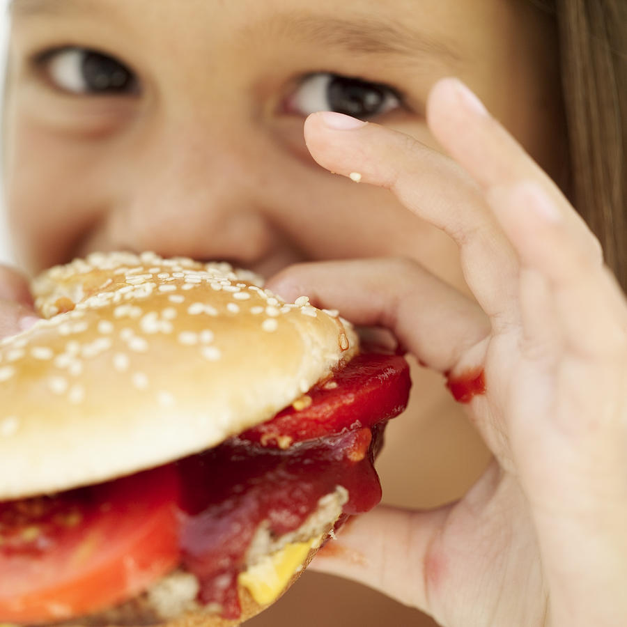 Close-up Of A Girl (6-7) Eating A Hamburger Photograph by Stockbyte
