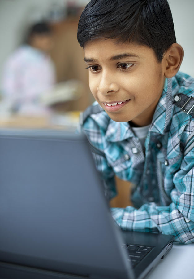 Close-up of a happy, Indian boy using laptop Photograph by Gawrav