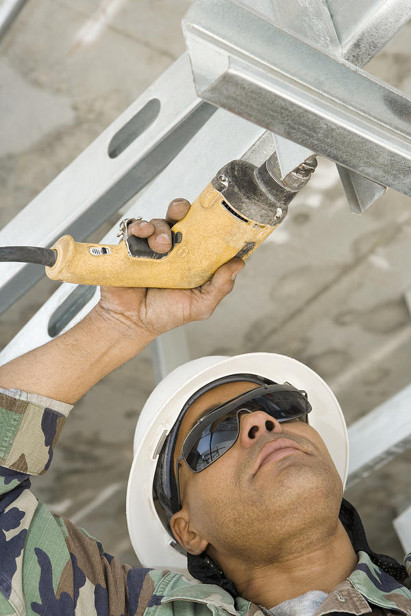 Close-up of a male construction worker working with a hand drill Photograph by Glowimages