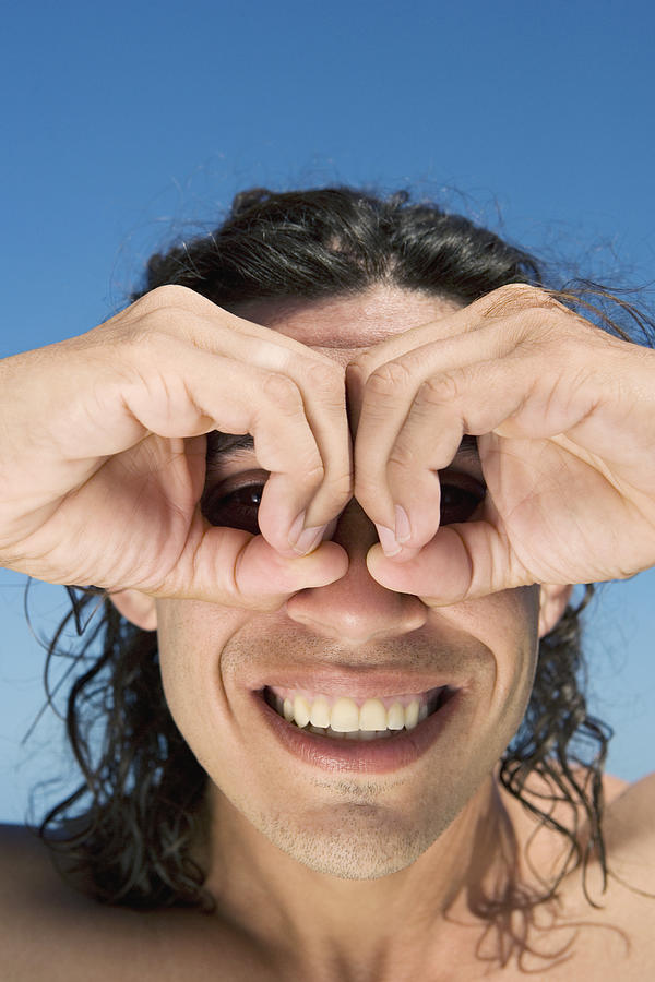 Close-up of a mid adult man making circles around his eyes with fingers Photograph by Glowimages