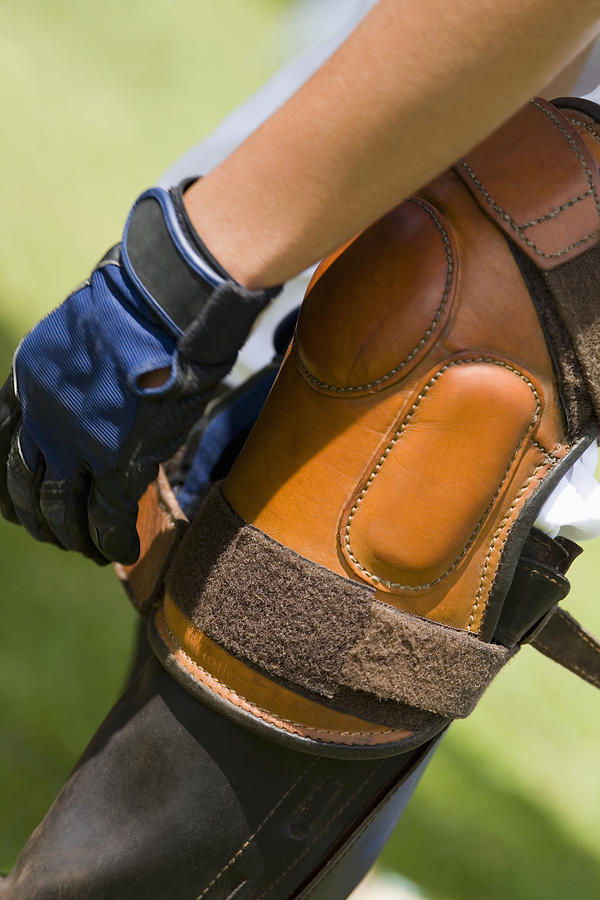 Close-up of a person tying a riding boot Photograph by Glowimages