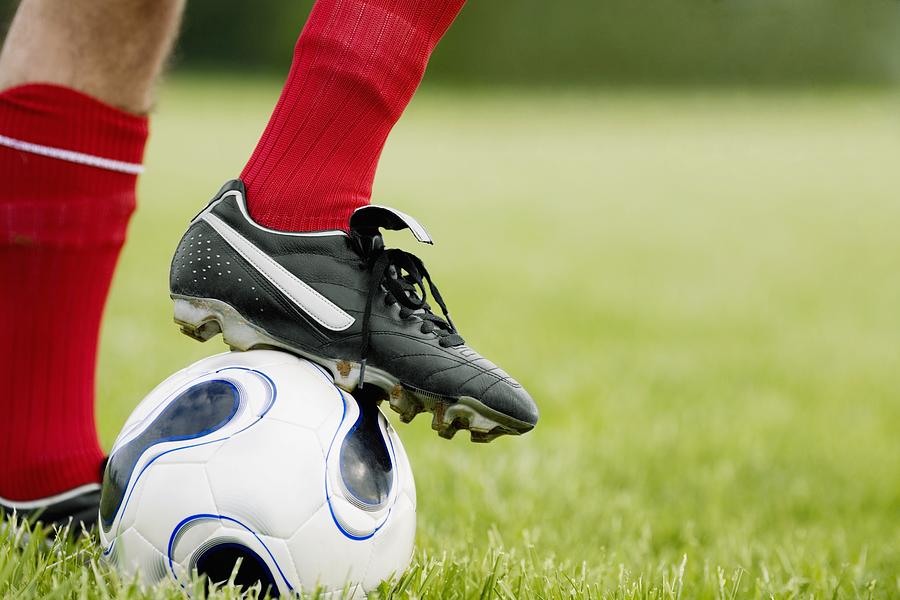 Close-up of a persons foot resting on a soccer ball Photograph by Glowimages
