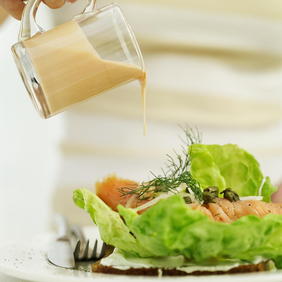 Close-up Of A Persons Hand Pouring A Jug Of Salad Dressing Over A Sushi Salad Photograph by Stockbyte
