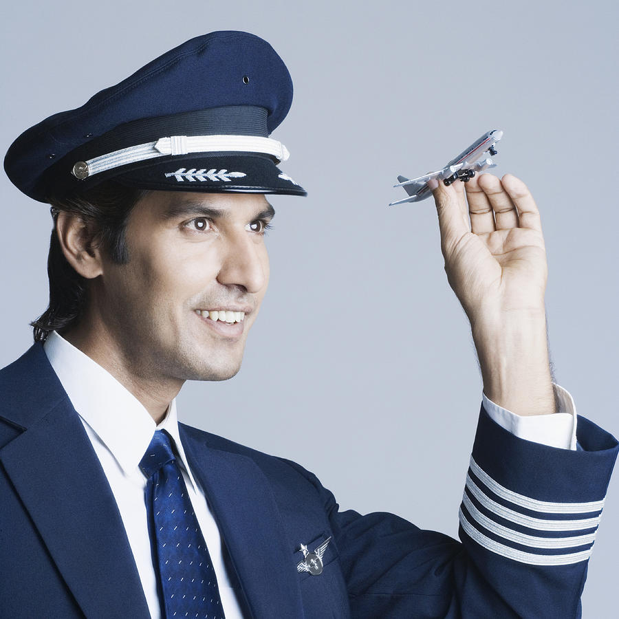Close-up of a pilot holding a toy airplane and smiling Photograph by Photosindia