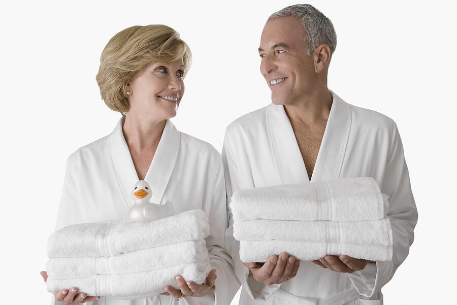 Close-up of a senior man with a mature woman standing together and holding folded towels Photograph by Glow Images
